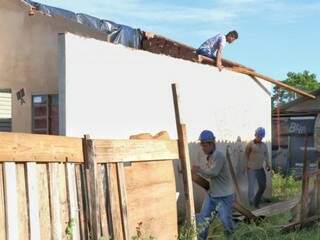 Equipe da Emha faz reparos na casa; moradores aguardam transferência de área e construção de casas (Foto: Henrique Kawaminami)