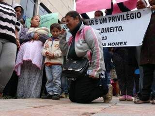 Invasora de terreno ajoelha-se em frente à governadoria para pedir regularização da situação em área que era de construtora mexicana (Foto: Henrique Kawaminami)