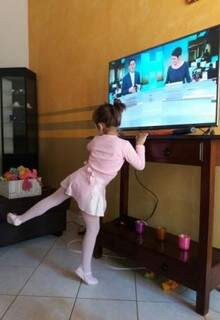 Em frente à TV e vestida com roupas de balé, ela treina as coreografias. (Foto: Arquivo Pessoal)