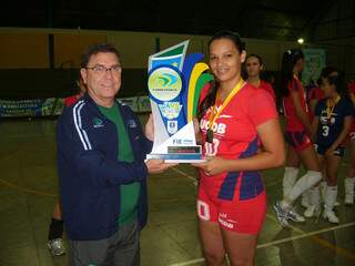 A capitã da equipe de Campo Grande recebe o troféu do título no vôleibol feminino. (Foto: Divulgação) 