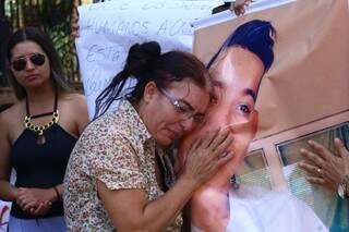 Marisilva Moreira da Silva, mãe do rapaz, chora abraçada a cartaz com foto de Wesner. (Foto: André Bittar)