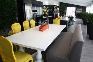 espaço gourmet tem mesa com cadeiras vibrantes em contraste com o sofá.