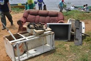Voluntários retiram móveis e TV das margens do Rio Paraná. (Foto:Divulgação)