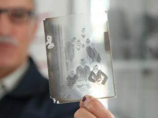 Nilson mostra um negativo de vidro, da sua coleção de câmeras e objetos antigos. (Foto: João Paulo Gonçalves)