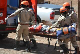 Após ser retirado de grua, trabalhador é colocado em ambulância. (Foto: Minamar Júnior)