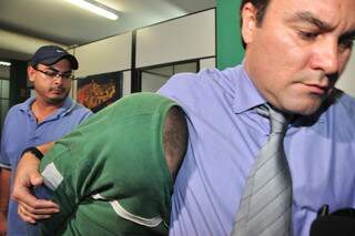 Cristhiano Luna escondeu o rosto ao sair de delegacia após depoimento. Ao lado dele, o antigo advogado. (Foto: João Garrigó)