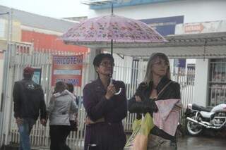 Mulheres se protegem da chuva, enquanto ao fundo, outra dupla se abraça para se aquecer (Foto: Marcos Ermínio)