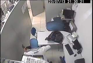 Ladrão obriga uma das vítimas a tirar dinheiro do caixa. (Foto: Reprodução/Circuito interno)