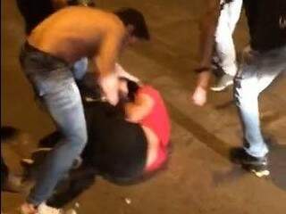 Jovem sendo agredido por dois rapazes enquanto pelo menos cinco homens assistem sem fazer nada (Foto: Reprodução)