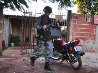 Policial sai da casa carregando a caixa com a munição. (Foto: João Garrigó)