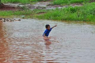 Criança brinca na água da chuva. (Foto: João Garrigó)