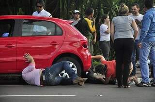 Pessoas tentando levantar o carro para tirar Thiago, que estava debaixo. (Foto: João Garrigó)