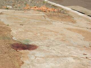 Mancha de sangue da vítima na calçada (Foto: Marlon Ganassin)