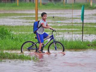 Aluno deixa escola de bicicleta, com água na canela. (Foto João Garrigó).