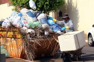 Funcionário do Coophamorena coloca os sacos em caçamba alugada por síndica para evitar lixo acumulado nas ruas. (Foto:Marcos Ermínio)