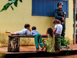 Crianças brincando ao lado da Penitenciária de Segurança Máxima, enquanto o policial cuida (Foto: Marcos Maluf)