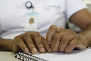 O caderno sempre fica ao lado de Áurea, para anotações. Tudo em braille. (Foto: Cleber Gellio)