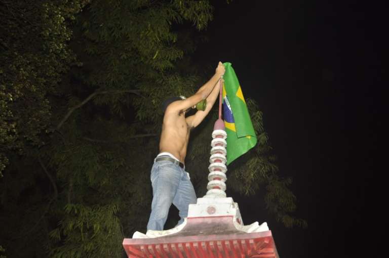 Jovem coloca bandeira do Brasil em monumento na Praça do Rádio. (Foto:João Garrigó)