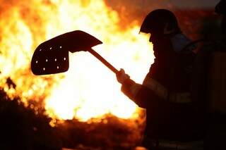 Cinco homens tentam controlar o fogo em frente ao aeroporto (Foto: Cleber Gellio)