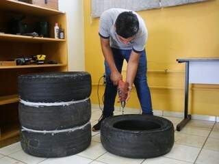 Aluno fura pneu para encaixá-lo nos demais com ajuda de parafusos. Goma branca entre os pneus é silicone usado para evitar que água vaze antes de ser tratada (Foto: Paulo Francis)