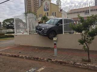 Carro fica pendurado no muro depois de destruir grade de igreja