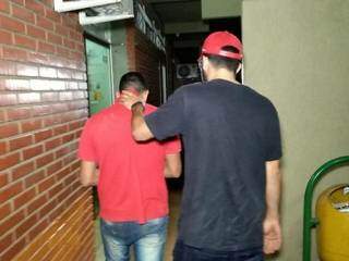 Suspeito, de camiseta vermelha, é levado para a delegacia (Foto: Adilson Domingos)