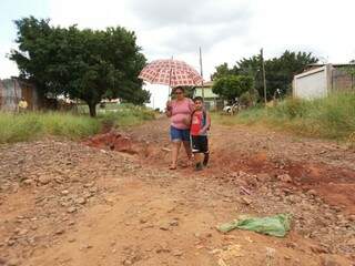 Ana Cáceres e o filho Ray superam todos os dias buracos no bairro para chegar a escola (Foto: Kleber Clajus)