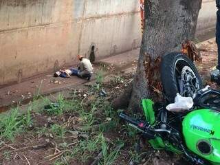 Moto após colisão com árvore e condutor sendo atendido dentro do córrego Segredo (Foto: Kerolyn Araújo) 