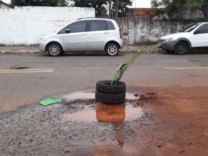 Moradores usam pneus e folhas para sinalizar buraco no bairro Amambaí