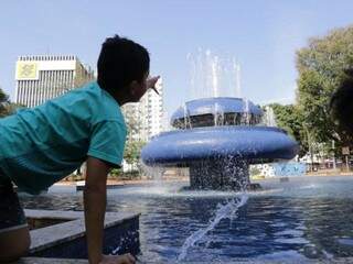Garoto brinca perto de fonte na Praça Ary Coelho, em Campo Grande; umidade do ar pode baixar de 12% na Capital. (Foto: Kísie Ainoã)