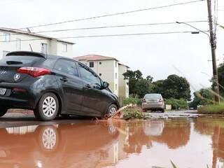 Veículos &quot;caem&quot; em cratera escondida pela poça na Avenida Três Barras. (Foto: Henrique Kawaminami)