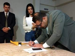 Observado por promotora, presidente da Câmara Alan Guedes assina notificação entregue a mando da Justiça (Foto: Diário MS)