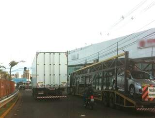 Caminhão cegonha estaciona para descarregar veículos na rua Joaquim Murtinho. 