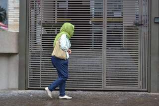 Mulher se protege da chuva que caiu, há pouco, no centro da Capital (Cleber Gellio)