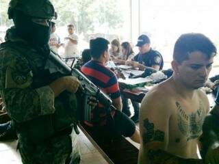 Policial paraguaio vigia presos quinta-feira; à direita está Evandro Padilha, que seria membro do PCC (Foto: ABC Color)