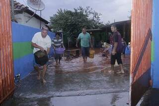 Vizinhos ajudam a retirar água da casa de moradora prejudicada pela chuva (Foto: Alan Nantes)