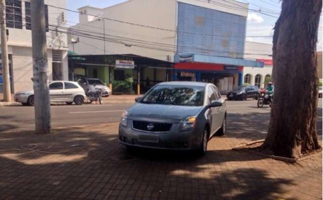 Mesmo com estacionamento ao lado, motorista para em cima da cal&ccedil;ada