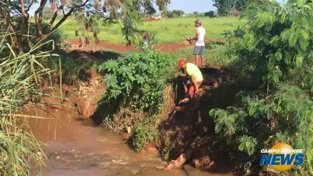 Ponte cai e moradores atravessam c&oacute;rrego a p&eacute; para chegar ao trabalho