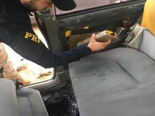 PRF retirando tablete de maconha escondido em veículo conduzido por jovem de 23 anos (Foto: Divulgação)