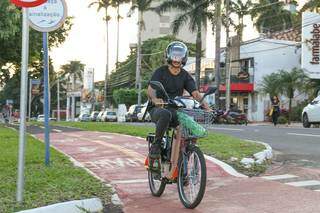Homem usando capacete para se locomover com bicicleta motorizada pela Avenida Afonso Pena (Foto: Paulo Francis)
