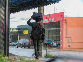 Sem guarda-chuva, o jeito foi se proteger da garoa com a mala mesmo (Foto: Marcos Maluf)