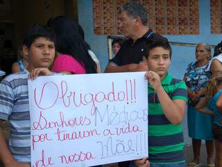 Meninos seguram cartaz durante manifestação após a morte da mãe deles (Foto: Simão Nogueira)