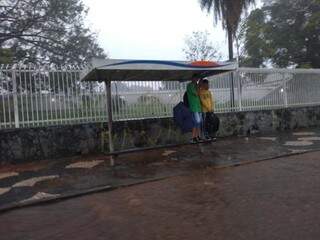 Estudantes tentando se proteger da chuva em ponto de ônibus (Foto: Geisy Garnes)
