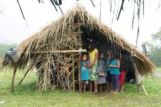 Crianças indígena se abrigando da chuva na área de retomada.