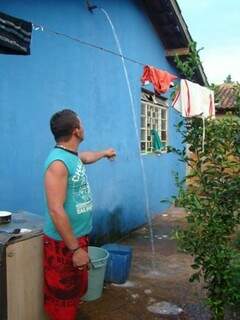 Trabalhador mostra cano de água utilizado para o banho. (Foto: Divulgação)