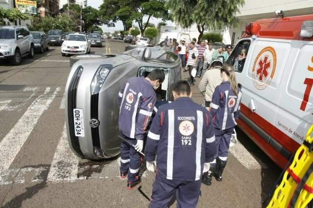 Ve&iacute;culo avan&ccedil;a no &quot;amarelo&quot;, bate em carro, tomba e fere dona de casa
