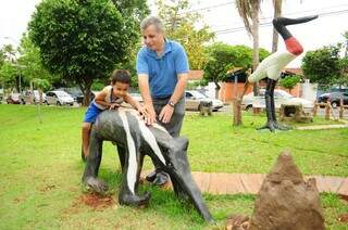 Em cima da escultura, Pedro explica ao pai que o tamanduá está comendo formigas. (Foto: Rodrigo Pazinato) 