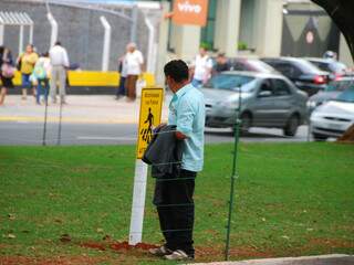 No meio do canteiro, pedestre lê a placa que pede a travessia na faixa. (Foto: Rodrigo Pazinato)
