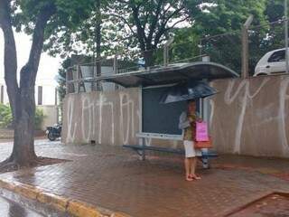 Mulher com guarda-chuva em ponto de ônibus na Afonso Pena. (Yarima Mecchi)