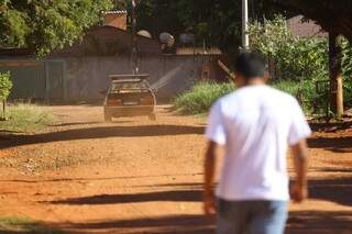 Moradores do Itamaracá caminha em rua sem asfalto, seguindo poeira deixada por veículo em movimento. (Foto: André Bittar)